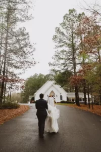 wedding couple walking back to the wedding chapel at evergreen wedding venue in rainbow city alabama
